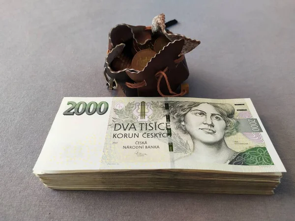 チェコの王冠 チェコのお金 2千枚の紙幣が大きな山の中に積み上げられ 50枚のクラウンコインを持つレザーポットの隣にあります ストックフォト