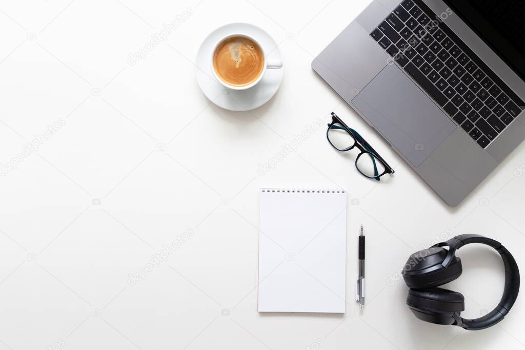Online education. Laptop, glasses, cup of coffee, notebook, pen and headphones on white table. Copy space for text.