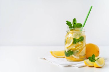 Mason kavanozunda taze limonata, kağıt kamış, limon dilimleri ve beyaz peçetede nane. Boşluğu kopyala.