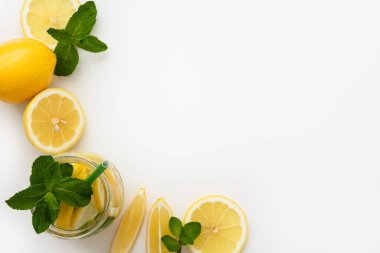Limonata yapmak için gerekli malzemeler. Yeşil kağıt kamışlı Mason kavanozu, limon dilimleri ve beyaz arka planda nane. Boşluğu kopyala.