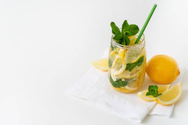Cam kavanozda taze limonata, kağıt kamış, limon dilimleri ve beyaz peçetede nane. Tazeleyici yaz içeceği. Boşluğu kopyala.