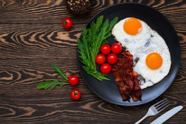 Yağda yumurta, pastırma, kiraz domatesleri ve ahşap masada roket salatası. Evde lezzetli bir kahvaltı. Düz yatıyordu.