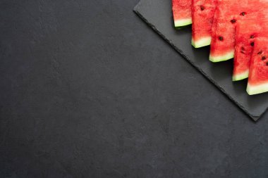Siyah arka planda siyah tabakta taze karpuz dilimleri. Boşluğu kopyala. 