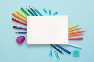 Mavi arka planda boş sayfası olan keçeli kalemlerin ve renkli kalemlerin üst görünümü. Okula dönelim. Gökkuşağı. Boşluğu kopyala. 