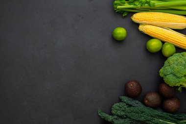 Kereviz, mısır, lahana, brokoli, avokado ve limon manzarası. Siyah arka planda, kopyalama alanı olan çeşitli sebzeler. Sağlıklı yaşam tarzı.