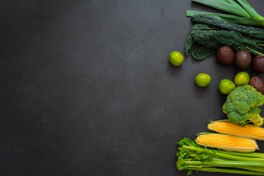 Kereviz, mısır, lahana, brokoli, pırasa, avokado ve limon manzarası. Siyah arka planda, kopyalama alanı olan çeşitli sebzeler. Sağlıklı yaşam tarzı.
