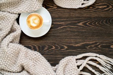 Sonbahar arkaplanı. Kahvenin en üst görüntüsü ve ahşap masaya ekose örgü. Fotokopi alanı olan rahat ve sıcak bir daire. Hygge konsepti.