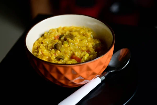 Bir kase yulaf ve mercimek, yanında beyaz kaşıkla siyah bir tabakta lapa..