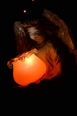 Turuncu bir lambayla aydınlatılan bir meleğin altını kapat