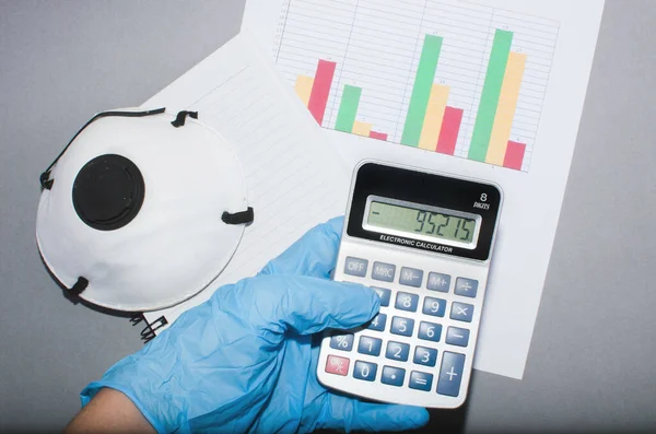 stock image hand with glove and calculator. Mask and business statistics.