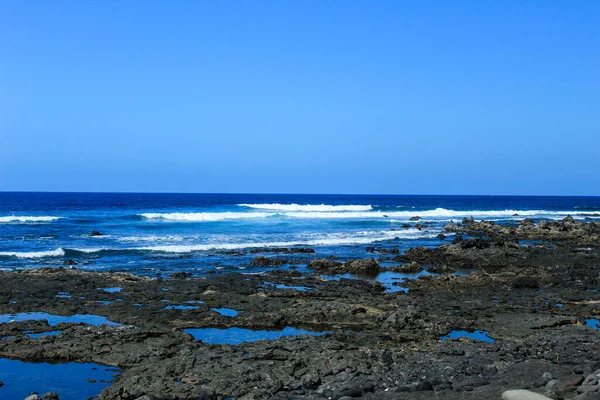 Praia Rochosa Preta Com Ondas Pequenas Céu Azul Claro — Fotografia de Stock