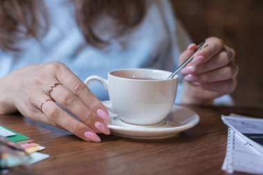 Bir fincan çayla masada oturan bir kadın.