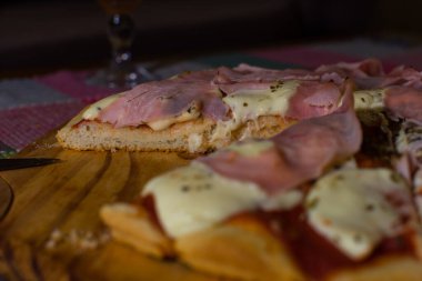 Jambon ve peynirli pizza. Tahta tepside kesilmiş.