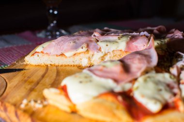Jambon ve mozzarella pizza. Tahta tepside kesilmiş.