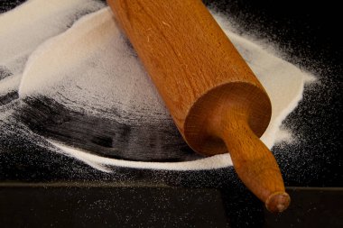 Siyah zemin üzerinde un olan yuvarlanan iğne.