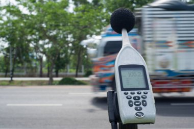 Measuring the noise of cars on the road with a sound level meter. clipart