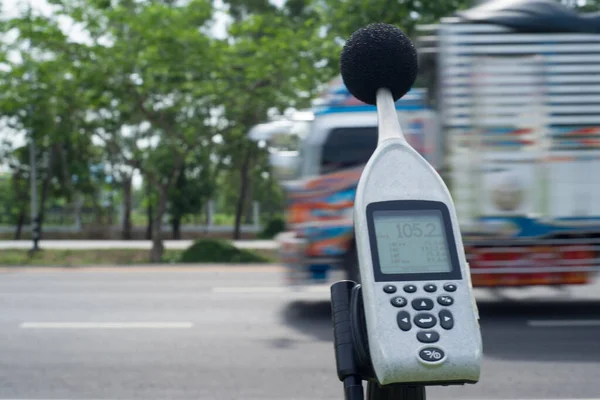 Measuring the noise of cars on the road with a sound level meter.