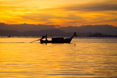 Altın sabah ışığı. Balıkçılar sabahın erken saatlerinde balık tutuyor. Bir balıkçının hayatı. Denizde balıkçılar. Fotoğrafçı Silhouet. Balıkçı teknesi..