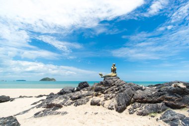 Kaya üzerinde deniz kızı heykeli olan gökyüzü ve sahil manzarası; Songkhla Tayland