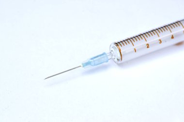 Beyaz zemin üzerinde tıbbi şırınga olan yakın çekim iğnesi