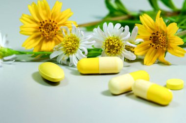 Sarı ve beyaz çiçekli ilaç hapları.                               