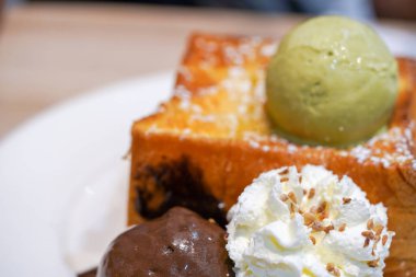Beyaz tabak ahşap masada dondurmalı ballı tost.