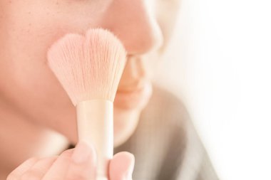 Güzel kız yanağına allık sürüyor. Güzellik Makyajı.