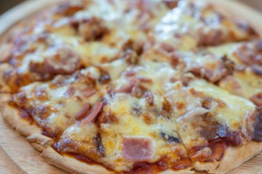 Yakın plan sıcak pizza dilimi üzerine jambon sosisi ve mozzarella peyniri damlıyor..