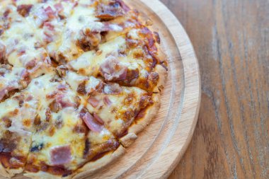 Yakın plan sıcak pizza dilimi üzerine jambon sosisi ve mozzarella peyniri damlıyor..