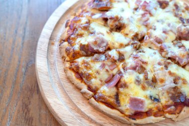 Yakın plan sıcak pizza dilimi üzerine jambon sosisi ve mozzarella peyniri damlıyor..