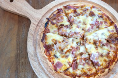 Yakın plan sıcak pizza dilimi üzerine jambon sosisi ve mozzarella peyniri damlıyor..