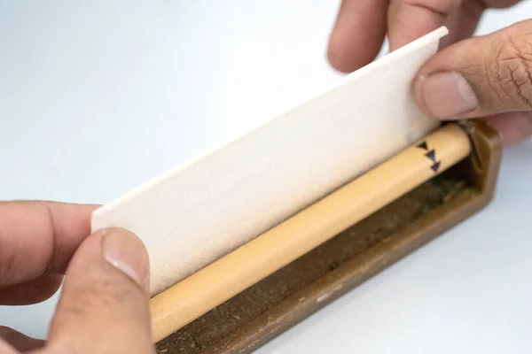 Hands making Marijuana joint from cigarette rolling machine, paper, Making cigarettes with pipe tobacco.