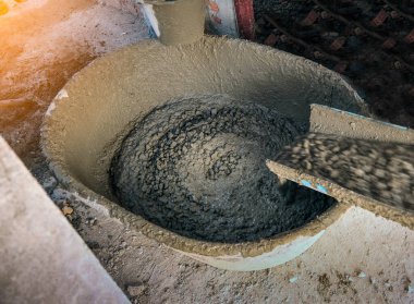 İnşaat alanındaki büyük havzaya beton karıştırıcı kamyonu döküyor.