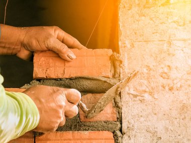 Duvarın iç duvarına tuğla döşeyen duvarcı işçiyi kapat.