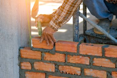 Dış duvarları tuğlayla örmek için mala ve aletler kullanan sanayi işçisi