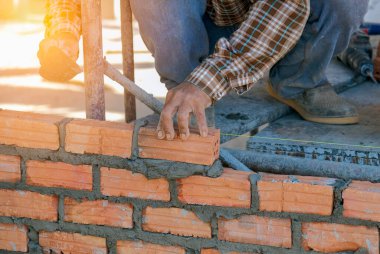 Dış duvarlar inşa ederken betona tuğla döşeyen sanayi işçisi