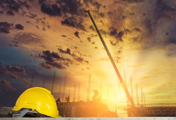 yellow safety helmet in construction side with sunset sky background