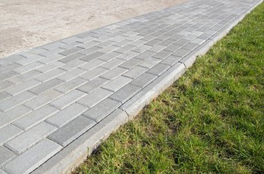 Yaya kaldırımı, gri asfalt levhalarla kaplı, toprağı solda toprak toprak ve sağda yeşil çimlerin düşük olduğu bölümlere ayırıyor. İki farklı madde arasında yürü.