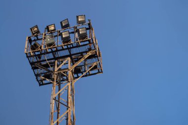 Mavi gökyüzünün arka planında demiryolu rayları üzerinde kullanılan sekiz lambadan oluşan eski bir dikdörtgen metal çerçeve üzerine monte edilmiş eski spot ışığı.