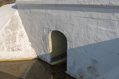 Painted white concrete drainage ditch design with hole in the form of an arch with the floor slab under road or rail surface with rain water at the bottom. Concept: protecting the road from drowning clipart