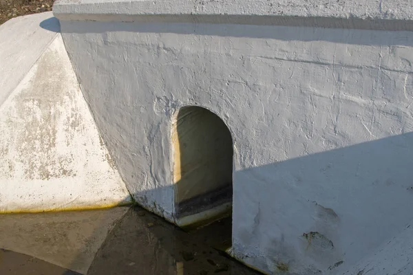 Painted white concrete drainage ditch design with hole in the form of an arch with the floor slab under road or rail surface with rain water at the bottom. Concept: protecting the road from drowning