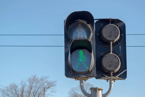 Her iki tarafa da bakan siyah iki kısımlı trafik ışığı, yeşil yürüyen kişinin sembolü olan alt kısımdaki demiryolu raylarının kesişimine yerleştirilmiş. Kavram: Açık erişim, izinsiz giriş serbest.