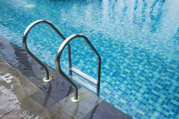 Grab bars ladder in the blue swimming pool