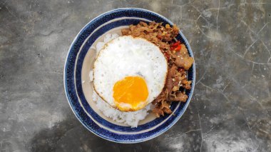 Bir kase kızarmış yumurta, domuz pastırması ve pilav.