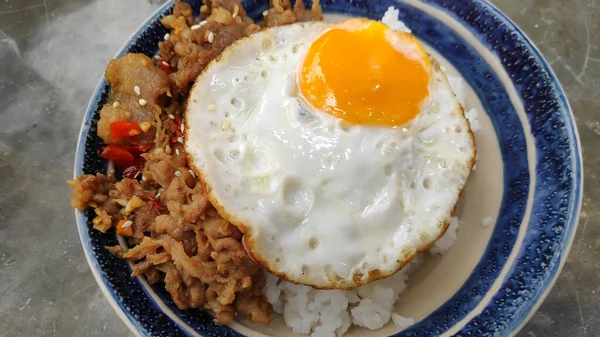 Bir kase kızarmış yumurta, domuz pastırması ve pilav.