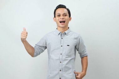 Neşeli, mutlu, kendinden emin Endonezyalı, parmak kaldıran, izole edilmiş bir geçmişi olan bir adam.
