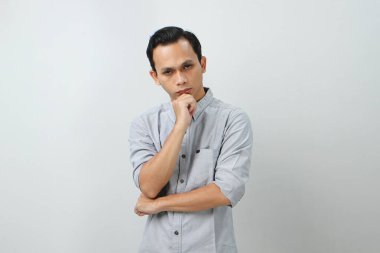 Ciddi bir suratı olan düşünceli Asyalı genç bir Endonezyalı soru hakkında düşünüyor, izole edilmiş arka planda kafa karıştırıcı bir fikir hakkında düşünceli.