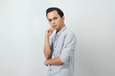 Ciddi bir suratı olan düşünceli Asyalı genç bir Endonezyalı soru hakkında düşünüyor, izole edilmiş arka planda kafa karıştırıcı bir fikir hakkında düşünceli.