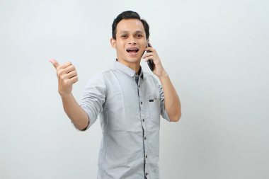 Mutlu Asyalı Endonezyalı baş parmak hareketi ile telefon görüşmesi yapıyor. izole arkaplan 