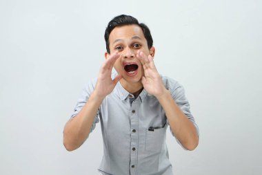 Genç Asyalı Endonezyalı bağırıyor ve izole edilmiş arka planda elleri ağızlarına dolanıyor.